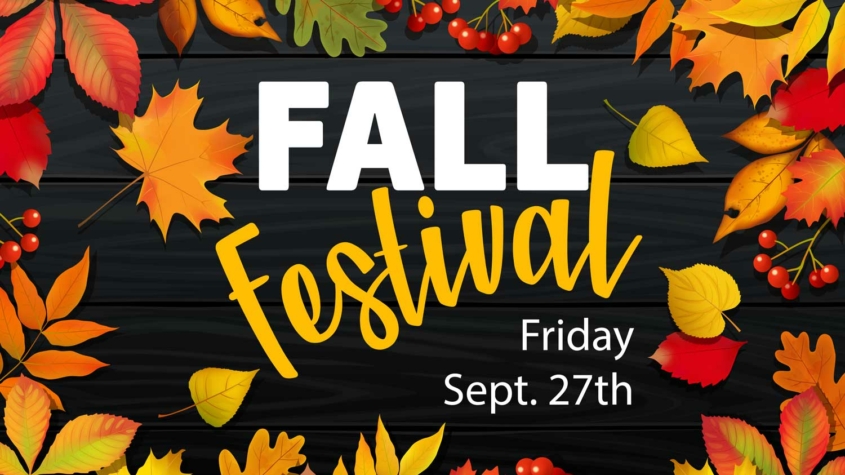 Colorful fall leaves and red berries surround bold text on a dark wood background. The text reads: "FALL Festival" in large white and yellow letters, with "Friday Sept. 27th" below in smaller white font. The leaves display shades of red, orange, yellow, and green, creating a festive autumn atmosphere.