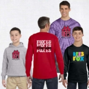 Four individuals modeling Ring Factory Elementary spiritwear. From left to right: a child wearing a gray hoodie with a red paw print and "RFES," a person in a red long-sleeve shirt with the word "Foxes" repeated on the back, a man in a purple tie-dye shirt with the same paw print and "RFES" logo, and another child in a black long-sleeve shirt with colorful text that reads "RFES Vibes Fox."